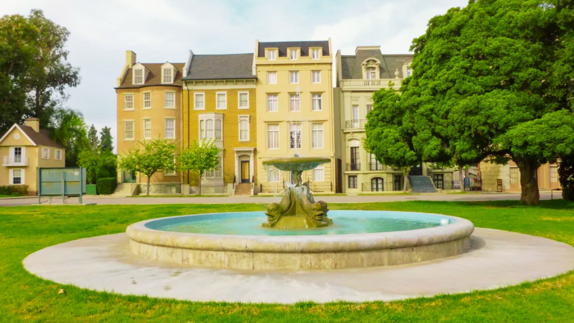 A fountain in front of a building, surrounded by trees and grass, where scenes from Friends were filmed.