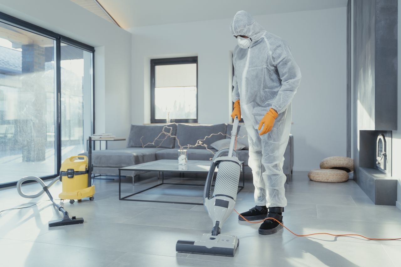 Professional deep cleaning a home in a protective suit